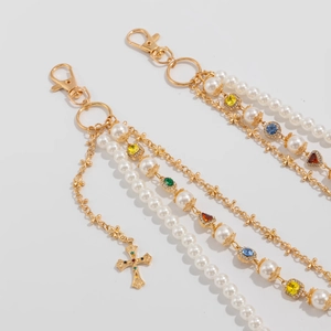 Detailed macro view of multi-layered gold chains with cross pendants and colorful gemstones