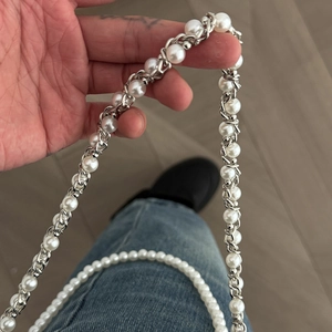 Detail der abnehmbaren Perlen- und Silberketten-Hose an einer blauen Jeanshose