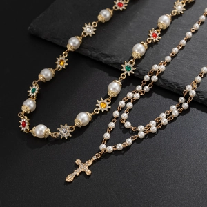Gros plan de colliers en perles avec pendentif croix serti de diamants sur pierre