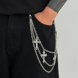 Detail of multi-layer silver pant chain with cross pendants on black denim jeans