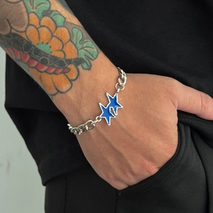 Bracciale cubano hip hop con ciondolo a stella in smalto blu sul braccio di un uomo