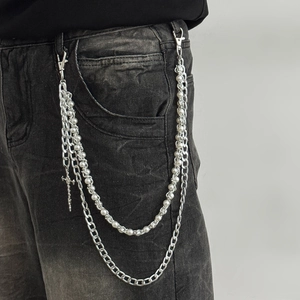 Detail of multi-layer hip hop waist chain with silver cross and faux pearls on denim