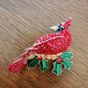 Sparkling cardinal bird brooch on holly branch with red crystals and green enamel detail