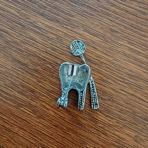 Detaillierte Rückansicht einer Zahn-Brosche mit sicherem Metallstift und Silber-Finish