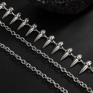 Detail shot of punk style silver metal pant chains with rivets on black volcanic rocks