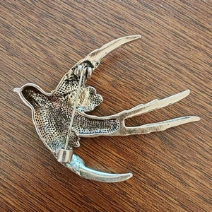 Back view of silver swallow bird brooch with vintage beaded texture and pin closure