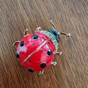 Détails de la broche coccinelle en émail rouge et noir avec des accents de strass brillants