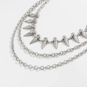 Detail of silver triple-layered metal pant chain with punk cone studs and sleek ring links