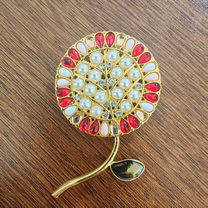 Dettaglio della spilla a girasole con perle, strass rosa e foglia in smalto nero