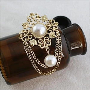 Vintage Baroque pearl brooch with gold filigree and elegant tassel hanging on a glass bottle