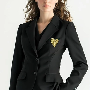 Detail of 3D gold heart brooch with hammered texture on a black suit jacket lapel