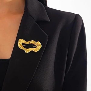 Macro detail of irregular 3D heart brooch with hand-hammered texture on black blazer