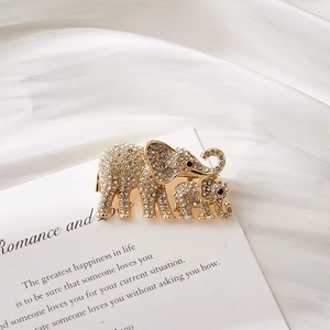 Elegant gold elephant brooch with sparkling zircons on white silk background