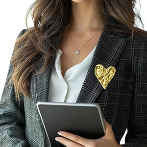 Artistic 3D heart brooch with hammered gold texture on a grey plaid blazer lapel