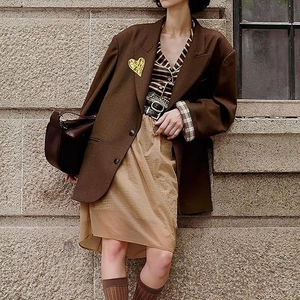 Irregular 3D sculpted gold heart brooch on a brown oversized wool blazer in retro style