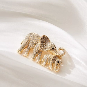 Detail of crystal paved mother and baby elephant brooch on soft white satin background