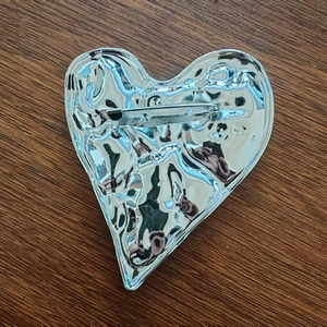 Detail view showing the back structure and horizontal safety pin clasp of a silver heart brooch