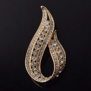 Détail d'une élégante broche dorée avec des strass étincelants au design de flamme en spirale