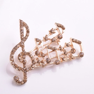 Détail macro de la broche note de musique dorée rose avec des strass étincelants