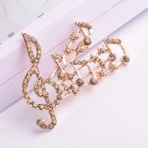 Vue macro d'une broche en forme de note musicale avec strass champagne sur alliage doré