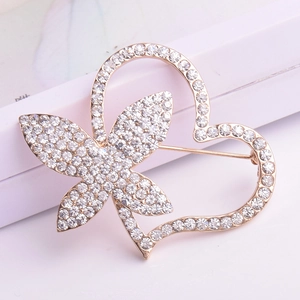 Detailed close-up of heart and butterfly brooch with sparkling crystals in gold finish