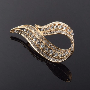 Détail macro d'une élégante broche en forme de feuille dorée avec strass scintillants