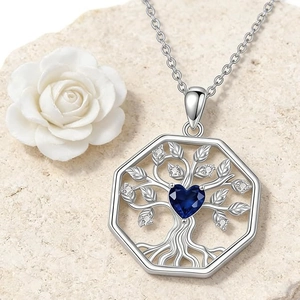 Macro view of silver tree of life pendant with heart-shaped blue gem on stone
