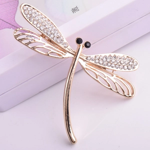 Detailed close-up of a luxury dragonfly brooch with sparkling rhinestones and golden plating
