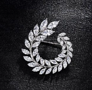 Detail of zircon wheat wreath brooch with silver metal base on black leather background