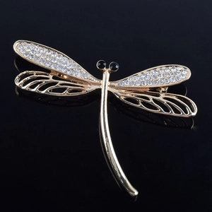 Macro detail of golden dragonfly brooch with white rhinestones and hollow wing design