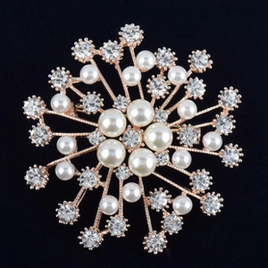 Détail macro d'une broche flocon en or rose avec perles blanches et cristaux étincelants