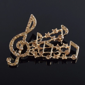 Macro d'une broche note de musique avec strass champagne sur une surface noire polie