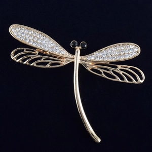 Elegant gold dragonfly brooch with crystal rhinestone wings on a black textured background
