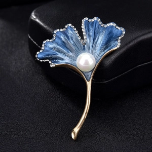 Vue macro détaillée de la broche feuille de ginkgo en émail bleu avec perle et strass