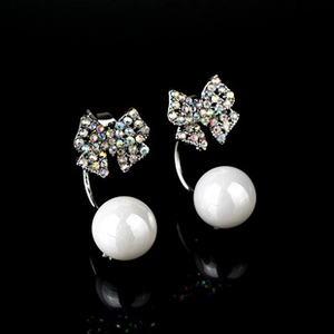Close-up of bowknot pearl earrings with rainbow rhinestones on black background