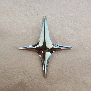 Détail d'une broche en métal étoile à quatre branches chromée sur fond de cuir
