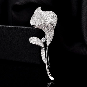 Detailed view of silver Calla Lily brooch with micro-pave zircons on a black silk box