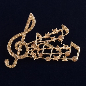 Élégante broche note de musique dorée avec strass champagne sur fond de velours noir