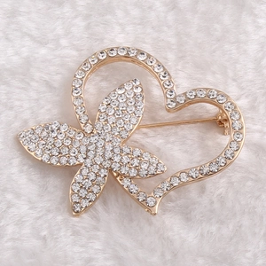 Close-up of heart and bow brooch in gold alloy with sparkling white crystals