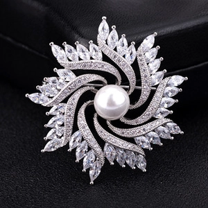 Macro view of snowflake swirl brooch with large pearl and sparkling zircon petals