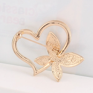 Detail shot of golden hollow heart and butterfly brooch showing back pin closure