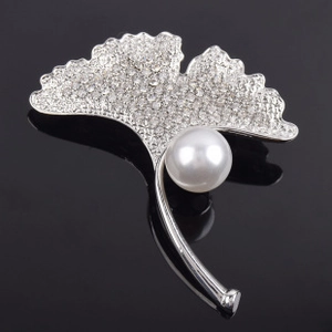 Détail macro d'une broche feuille de ginkgo avec cristaux et une grande perle blanche