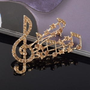 Détail de la broche note de musique dorée sertie de strass couleur champagne