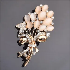Détail d'une broche bouquet dorée avec opales champagne et ruban en zircons