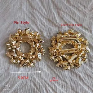 Détail d'une broche fleur dorée de 5cm et d'un clip pour foulard en soie texturé