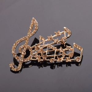 Vue macro d'une broche note de musique avec strass champagne sur fond miroir noir