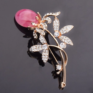 Nahaufnahme der goldenen Blumenbrosche mit rosa Edelstein und Strasssteinen