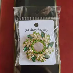 Détail de la broche couronne florale dorée avec cristaux verts et motifs de feuilles