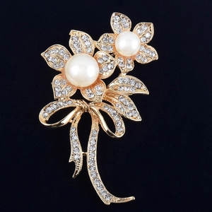 Vue détaillée d'une broche fleurie avec perles et cristaux sertis sur un fond noir uni