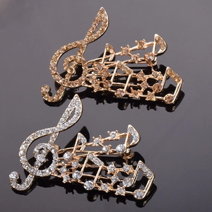 Détail de broches en forme de note de musique en or et argent avec strass brillants
